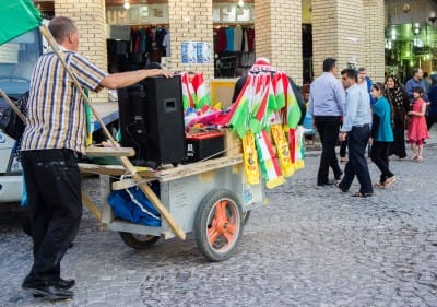 Ein fahrender Verkäufer mit Flaggen, Schals und weiterem Fanmaterial in den Farben Kurdistans und der Regierungspartei PDK