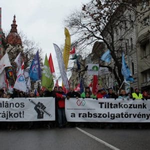 Proteste in Ungarn. Zwei Transparente an der Spitze der Demonstration samt Dutzenden Fahnen.